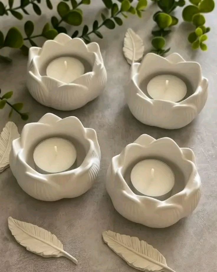 Four ivory lotus-shaped candle holders with tea lights