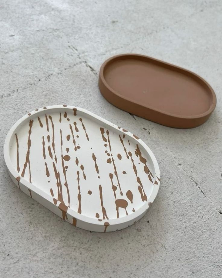 Ivory oval tray with brown abstract splatter pattern beside a plain brown tray