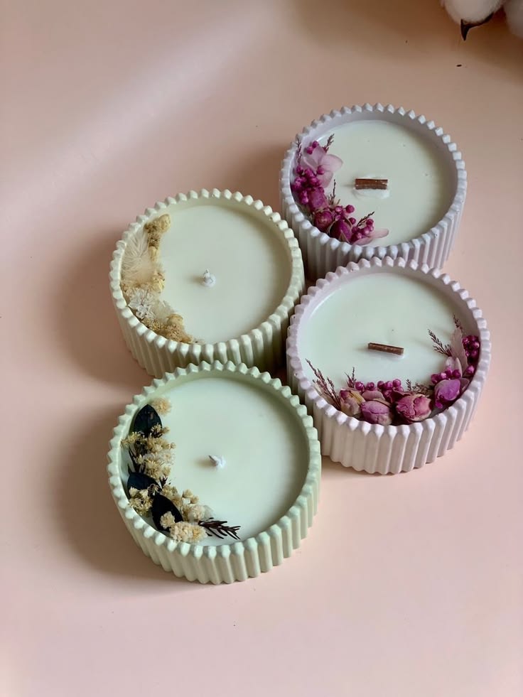 Fluted candles decorated with dried flowers on a pastel surface