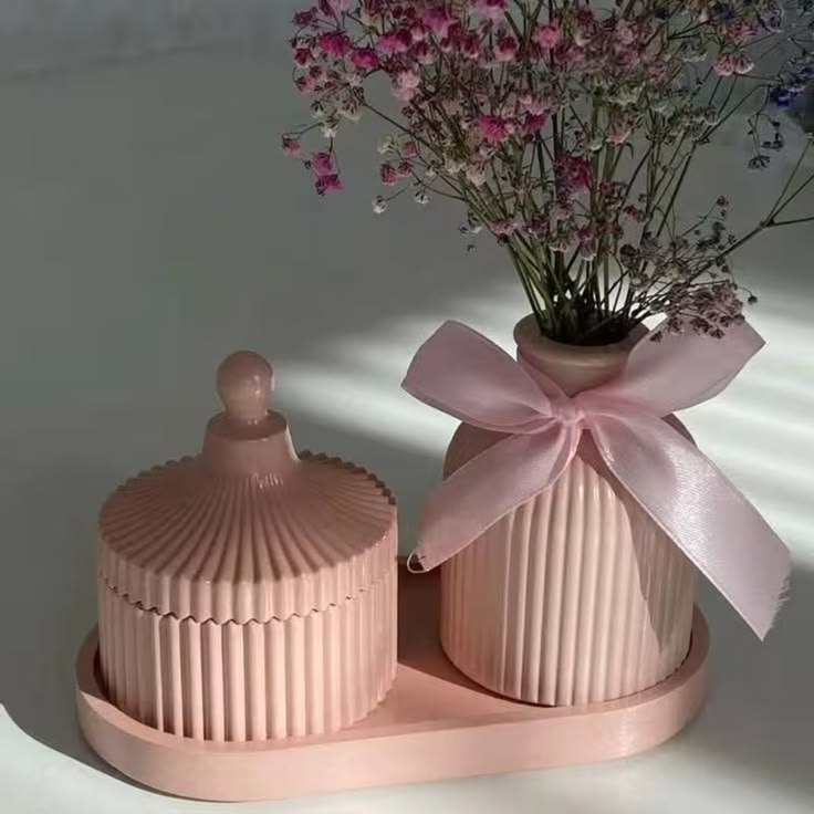 Pastel pink ribbed vase and lidded jar on an oval tray